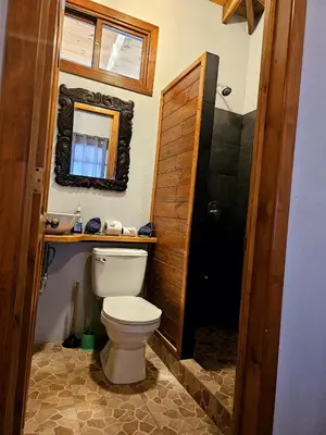 a bathroom with a toilet and a mirror at Cabaña junto al río in Naranjito