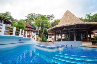 a swimming pool at a resort with a thatch roof at Mi Casa-stroll to the beach, ideal for 3-7 guest in Santa Cruz