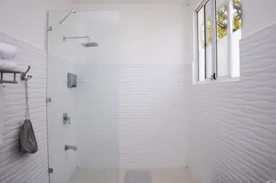 a white bathroom with a shower with a glass door at Mi Casa-stroll to the beach, ideal for 3-7 guest in Santa Cruz