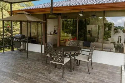 a patio with a table and chairs and a kitchen at La Cabaña in Heredia