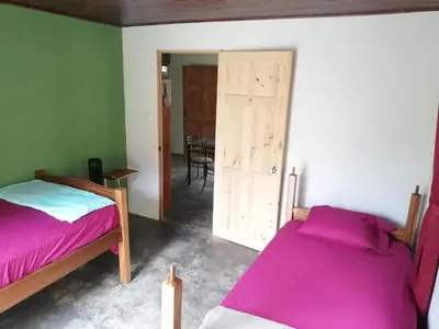 a bedroom with two beds and a dining room at Casa el Colibrí in Naranjo