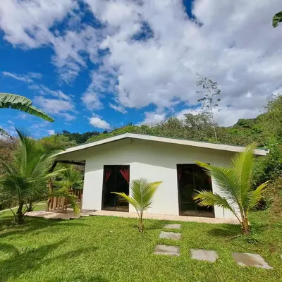 a small white house in the middle of a yard at Casa el Colibrí in Naranjo
