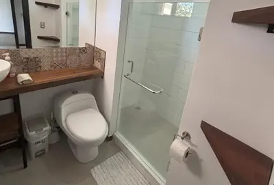 a bathroom with a toilet and a glass shower at Amazilia Guesthouse in Liberia