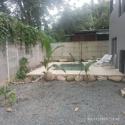 a backyard with a swimming pool and two chairs at Uvita Stone House in Uvita