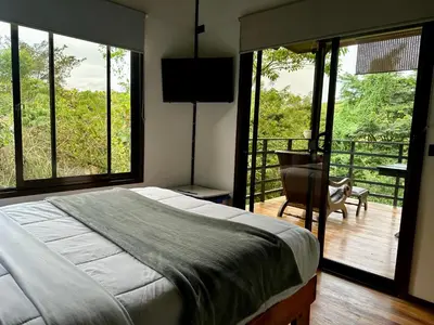 a bedroom with a bed and a balcony with a chair at Ceibo Lodge, great birdwatching in Bijagual