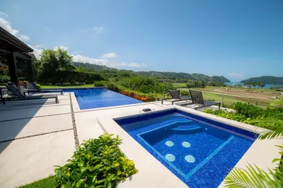a swimming pool in a yard with two chairs at Casa Blue Sail 6 bdrs ocean view in Los Suenos in Herradura