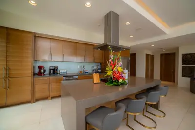 a large kitchen with a large island with chairs at Casa Blue Sail 6 bdrs ocean view in Los Suenos in Herradura