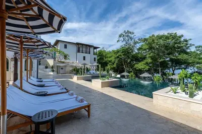 a row of chaise lounge chairs next to a swimming pool at Trendy Condo with Stunning Ocean Views and Exclusive Beach Club Access in Las Catalinas in Playa Danta