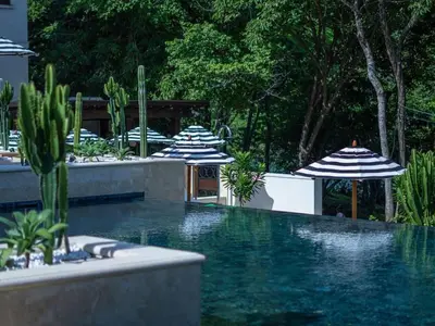 a swimming pool with umbrellas and cactuses at Trendy Condo with Stunning Ocean Views and Exclusive Beach Club Access in Las Catalinas in Playa Danta