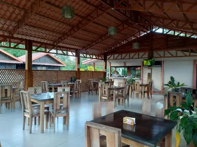 an empty restaurant with wooden tables and chairs at Cabinas Río Frío in San Rafael