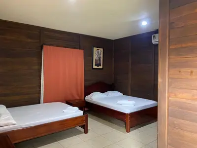 two beds in a room with wooden walls at Cabinas Río Frío in San Rafael