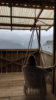 a woman sitting in a hammock on a porch at Finca Del Cielo in El Castillo de la Fortuna