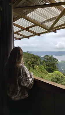 a woman looking out of a window at the ocean at Finca Del Cielo in El Castillo de la Fortuna