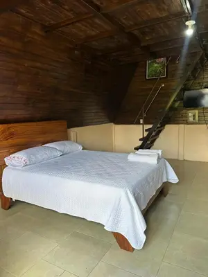 a bedroom with a large bed with white sheets at Bungalow Tenorio Mountain Lodge in Rio Celeste