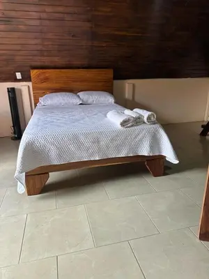a bed with a wooden headboard in a bedroom at Bungalow Tenorio Mountain Lodge in Rio Celeste