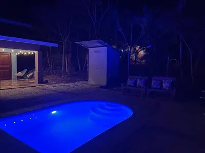 a blue swimming pool in a yard at night at Casa Encanto in Puntarenas