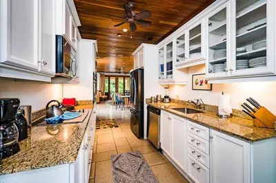 a kitchen with white cabinets and a ceiling fan at Sunset & OceanView Terrace, Pool, Beach and Grill in Tamarindo