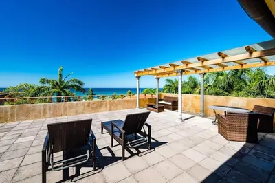 a patio with a table and chairs and the ocean at Sunset & OceanView Terrace, Pool, Beach and Grill in Tamarindo
