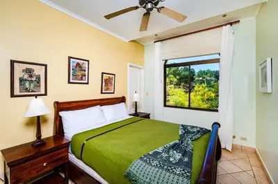 a bedroom with a green bed and a window at Family Setting, Big Pool Beach facing in towns in Tamarindo