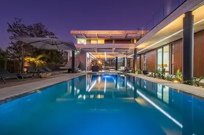 a swimming pool in front of a house at night at New 6 bd Modern Home Walk to Beach in Tamarindo
