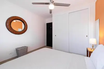a bedroom with a white bed and a mirror at Pool and Private rooftop access in town! in Tamarindo