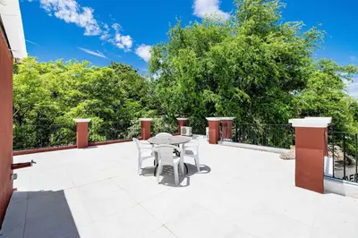 a patio with a table and chairs and trees at Pool and Private rooftop access in town! in Tamarindo