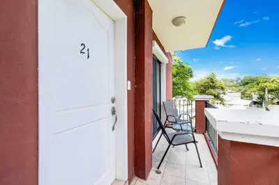 a porch with a white door and chairs on a balcony at Pool and Private rooftop access in town! in Tamarindo
