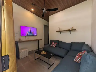a living room with a blue couch and a flat screen tv at Yellow House - Country house near La Fortuna in San Ramón