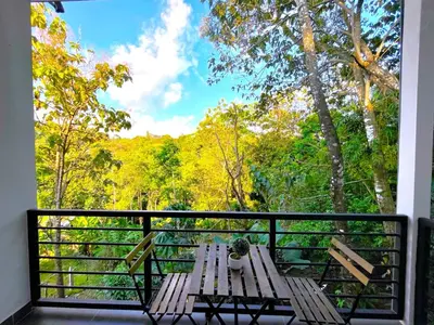 a balcony with a bench and a view of trees at Casa Tucan in Quepos