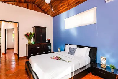 a bedroom with a large bed with a blue wall at Remodeled Casa Tropical w Private Pool in Tamarindo