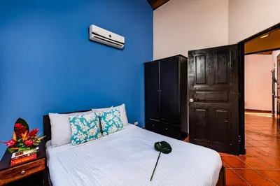 a bedroom with a bed with a blue wall at Remodeled Casa Tropical w Private Pool in Tamarindo