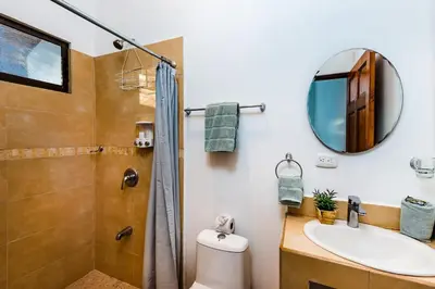 a bathroom with a shower and a sink and a mirror at Remodeled Casa Tropical w Private Pool in Tamarindo
