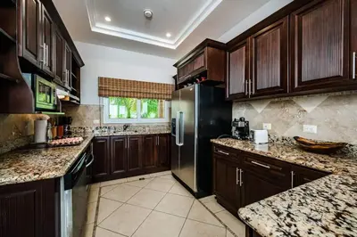 a kitchen with wooden cabinets and a stainless steel refrigerator at Oceanview Escape Large Pool and 247 Security! in Tamarindo