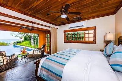 a bedroom with a bed and a patio with a pool at Exclusive Beachfront Villa Private Pool & BBQ in Tamarindo
