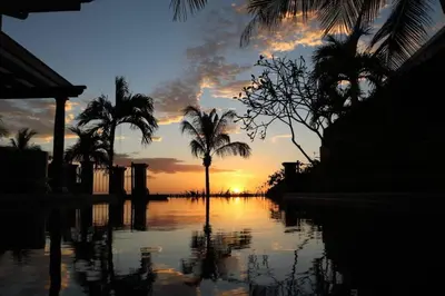a sunset with palm trees and a body of water at Exclusive Beachfront Villa Private Pool & BBQ in Tamarindo