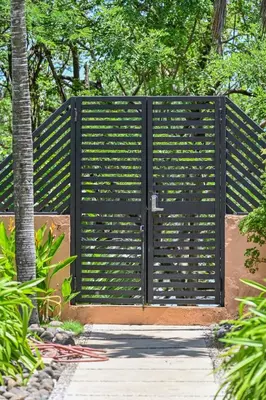 a gate in a garden with a palm tree at Beautiful beachfront 2BR condo, with full kitchen in Tamarindo