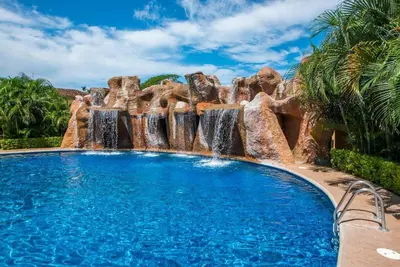 a pool in a resort with waterfalls at Beach Facing, large pool & guard in the town in Tamarindo