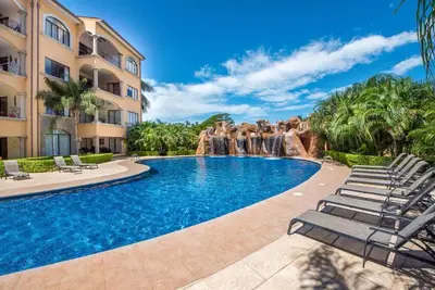 a swimming pool with a waterfall in a resort at Beach Facing, large pool & guard in the town in Tamarindo