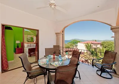 a dining room with a table and chairs on a balcony at Beach Facing, large pool & guard in the town in Tamarindo