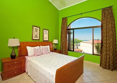 a green bedroom with a bed and a large window at Beach Facing, large pool & guard in the town in Tamarindo