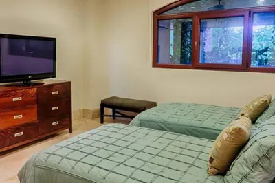 a bedroom with two beds and a flat screen tv at Beachfront, Sunset, & Ocean Views with Elevator in Tamarindo