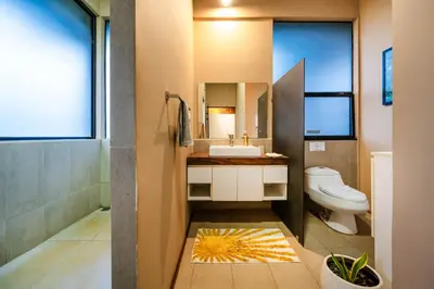 a bathroom with a toilet and a sink and a mirror at Oceanview and Private Pool 8 mins to Downtown in Hernández