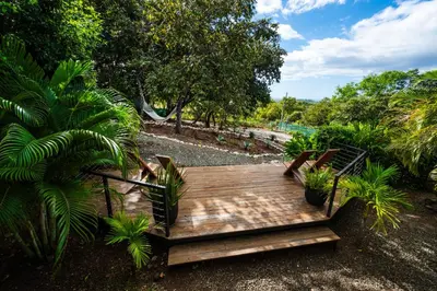 a wooden deck in a garden with plants at Oceanview and Private Pool 8 mins to Downtown in Hernández
