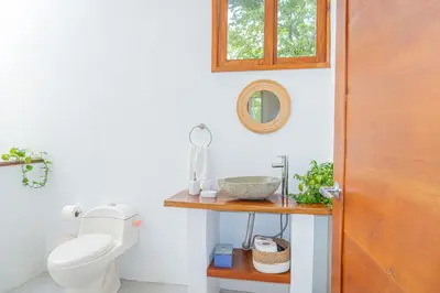 a bathroom with a toilet and a wooden door at Casa Serena Private pool 800m from the beach in Uvita