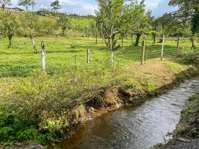 a river with a fence next to a field at Casa La Finca Private Pool / AC WiFi 300Mbps in Fortuna