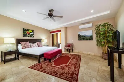 a large bedroom with a bed and a red couch at Beachfront, Sunset, & Ocean Views with Gas Grill in Tamarindo