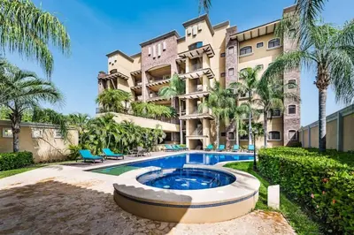 an apartment building with a swimming pool and palm trees at Beachfront, Sunset, & Ocean Views with Gas Grill in Tamarindo