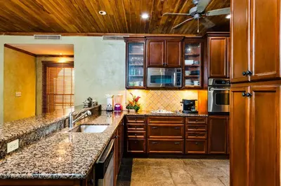 a kitchen with wooden cabinets and granite counter tops at Sunset view roof terrace, steps to the beach! in Tamarindo