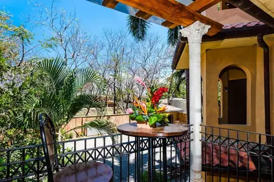 a balcony with a table with a vase of flowers at Sunset view roof terrace, steps to the beach! in Tamarindo