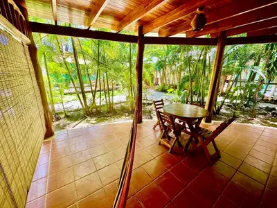 a porch with a table and chairs and trees at Pacifica Surf Studios in Santa Teresa Beach